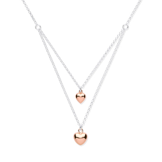 Two heart-shaped pendants on a silver chain against a white background